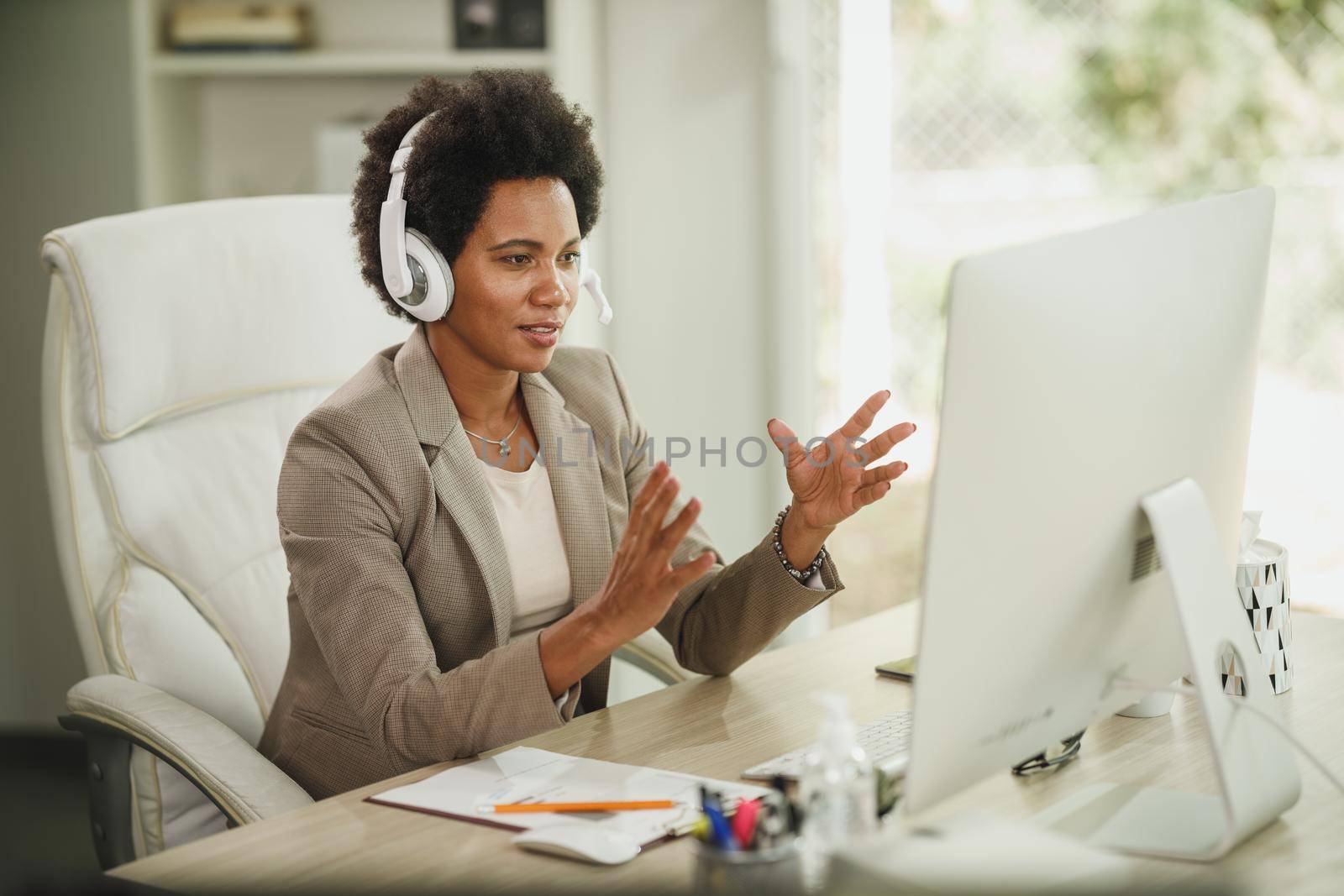 Shot of an attractive African businesswoman with headphones having video call while working on computer during corona virus pandemic.