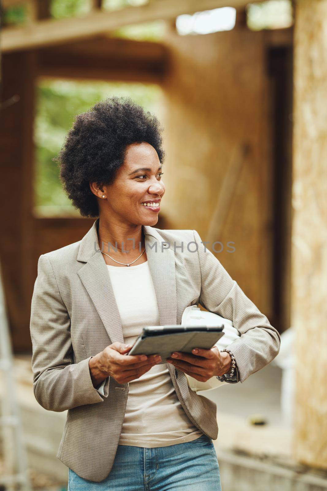 Shot of an African female architect using a digital tablet and checking construction site of a new wooden house.