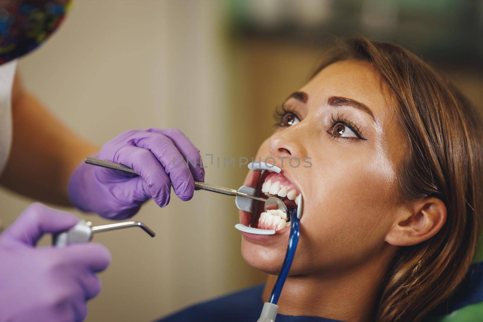 Cropped shot of a beautiful young woman is at the dentist. She sits in the dentist's chair and the dentist preparing to sets braces on her teeth putting aesthetic self-aligning lingual locks.