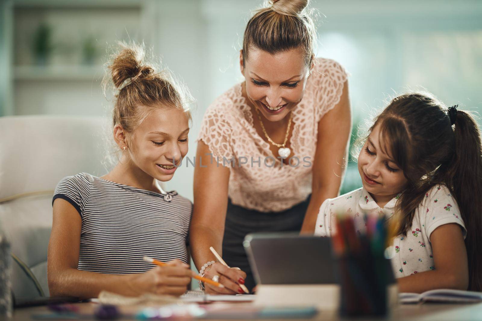 Shot of a beautiful young mother helping hers two daughters with homework during COVID-19 pandemic.