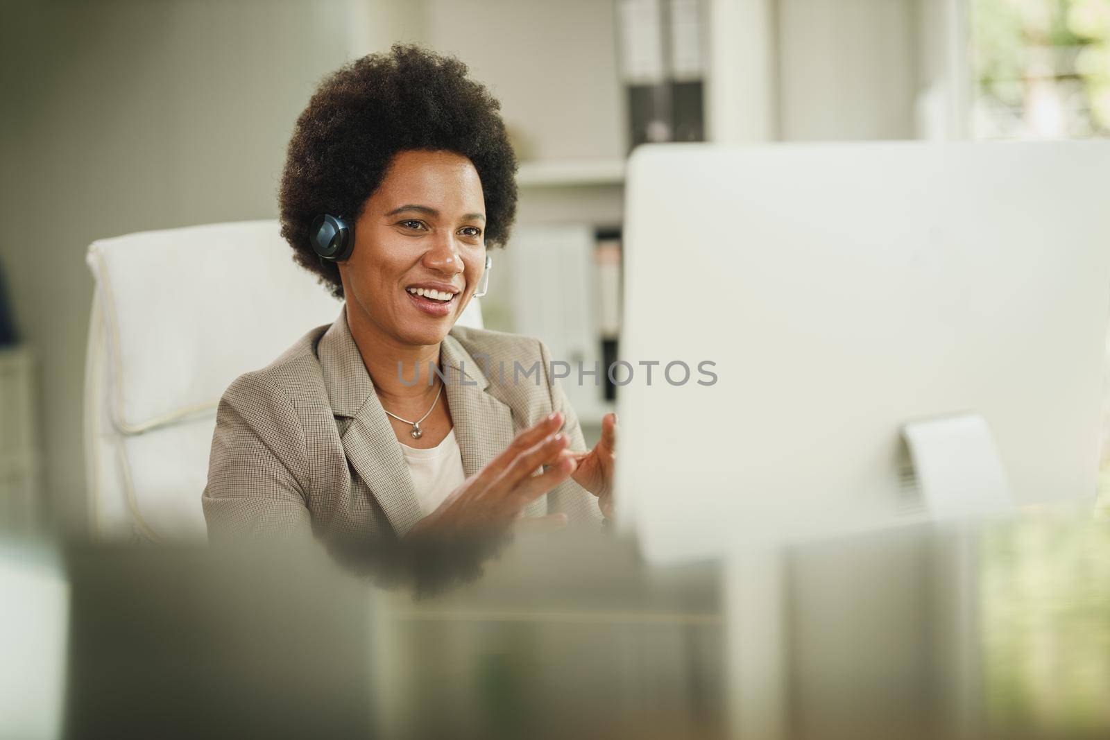 Shot of an attractive African businesswoman with headphones having video call while working on computer during COVID-19 pandemic.