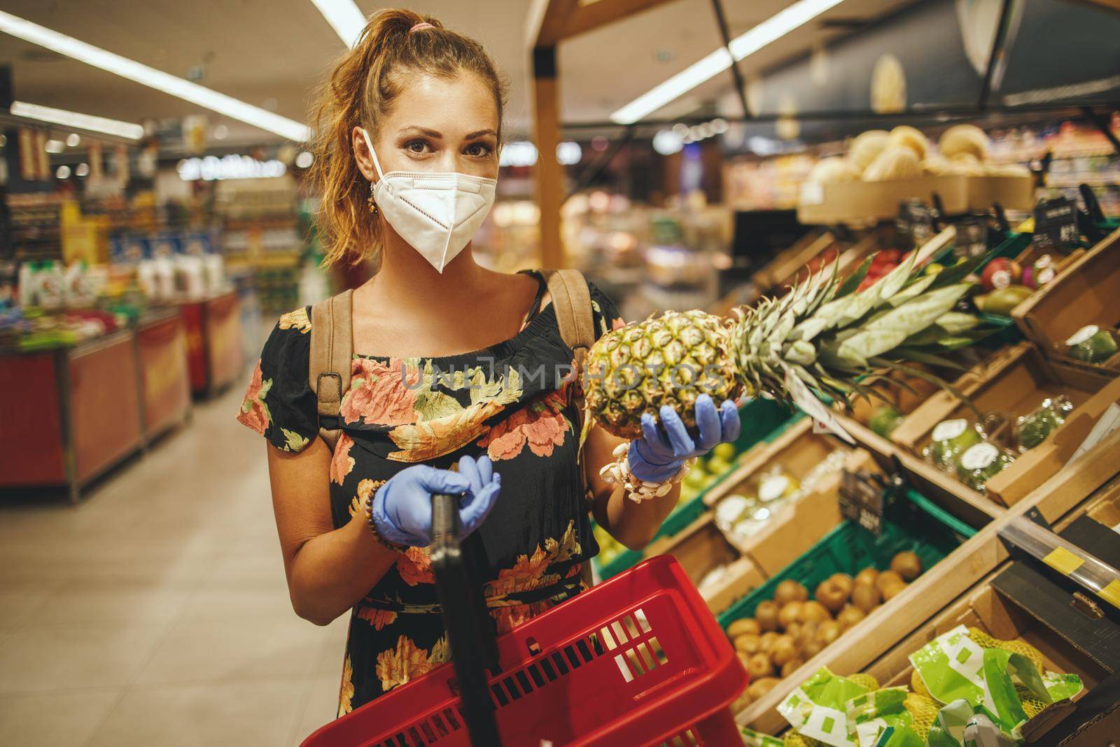 Shot of a young woman is wearing N95 protective mask while buying groceries in supermarket during Covid-19 pandemic.