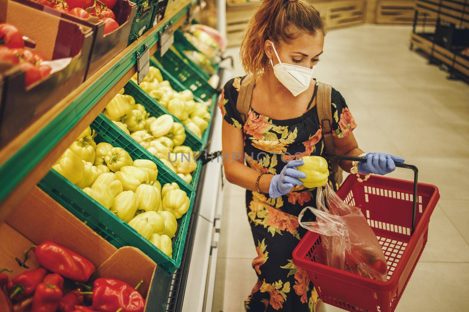 Shot of a young woman is wearing N95 protective mask while buying groceries in supermarket during Covid-19 pandemic.
