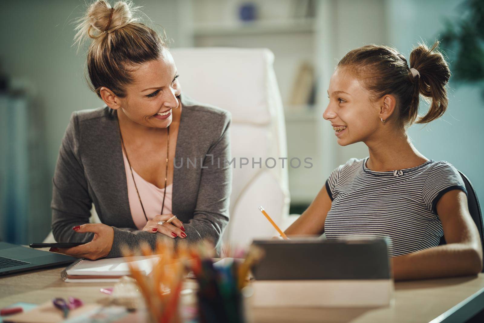 Shot of a beautiful young mother helping her daughter with homework during COVID-19 pandemic.