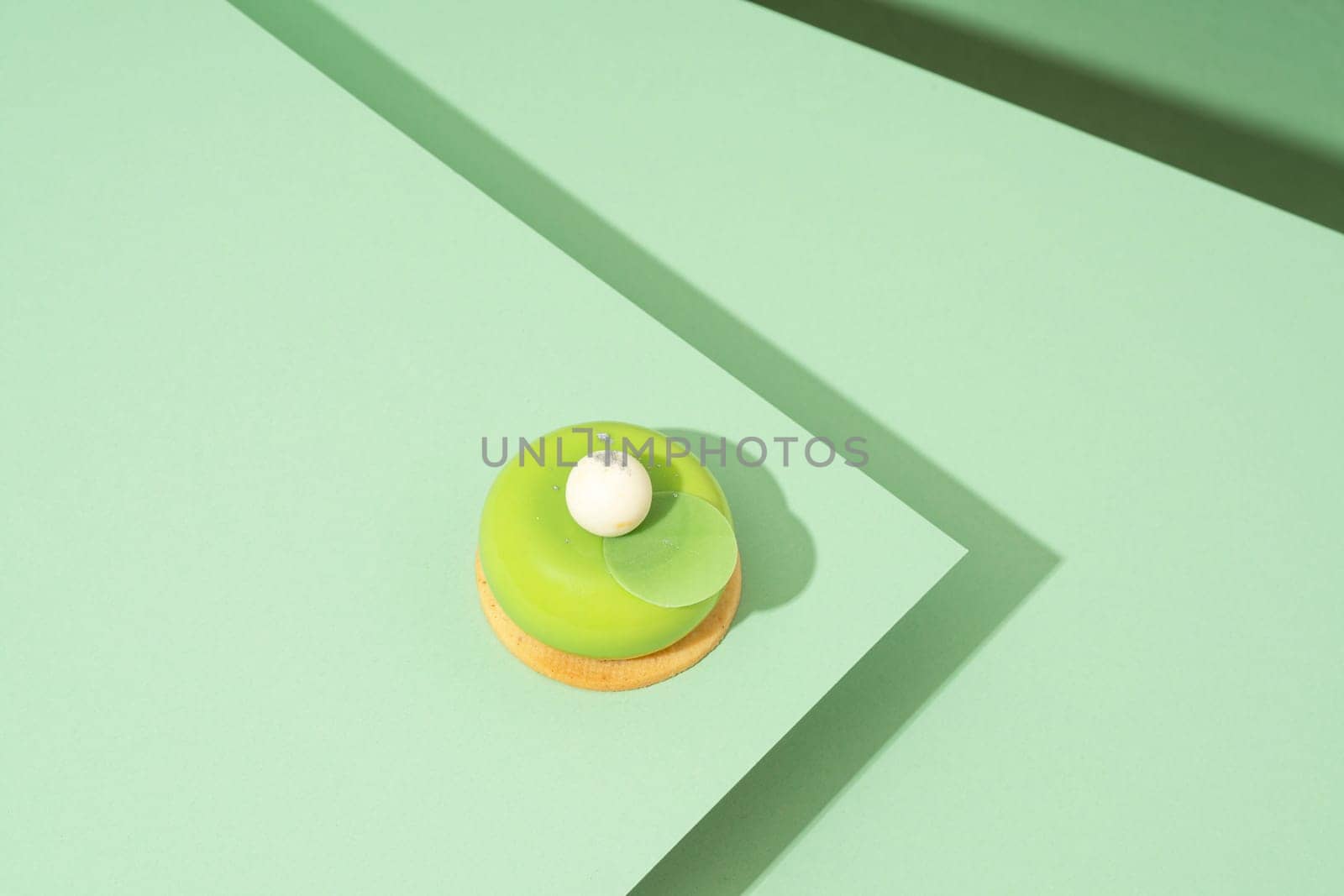 A freshly baked pastry with green and white icing, sitting atop a green-hued surface by A_Karim