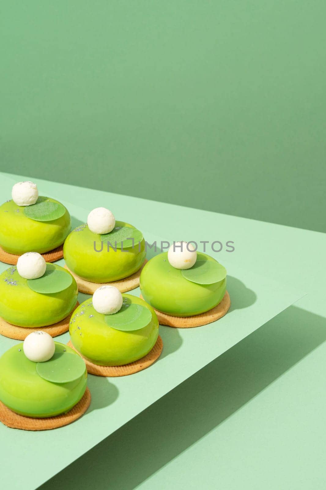 A platter of assorted green donut treats sits atop a wooden table by A_Karim