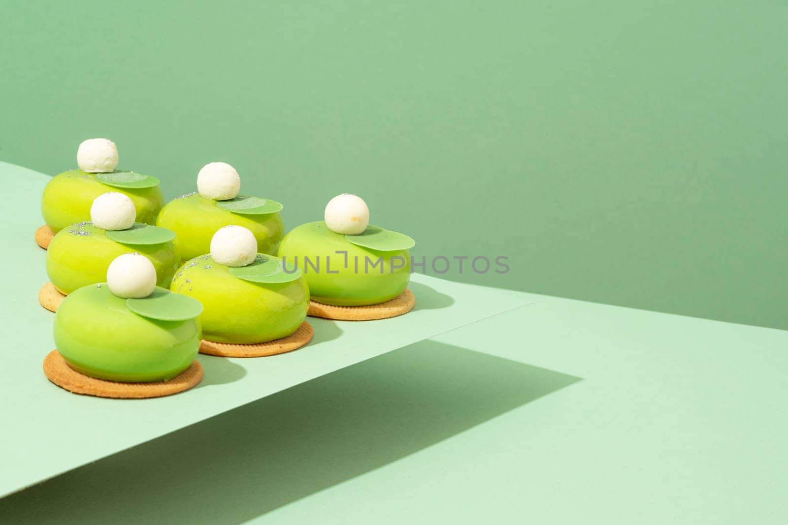 A platter of assorted green donut treats sits atop a wooden table