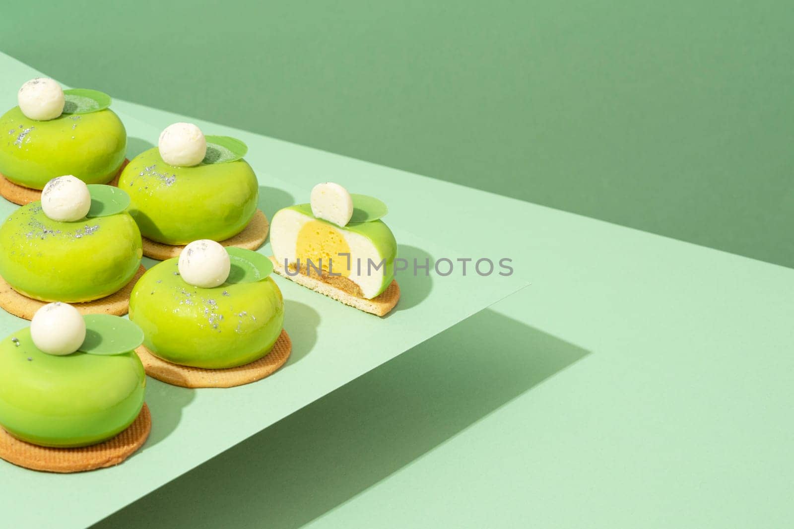 A platter of assorted green donut treats sits atop a wooden table by A_Karim