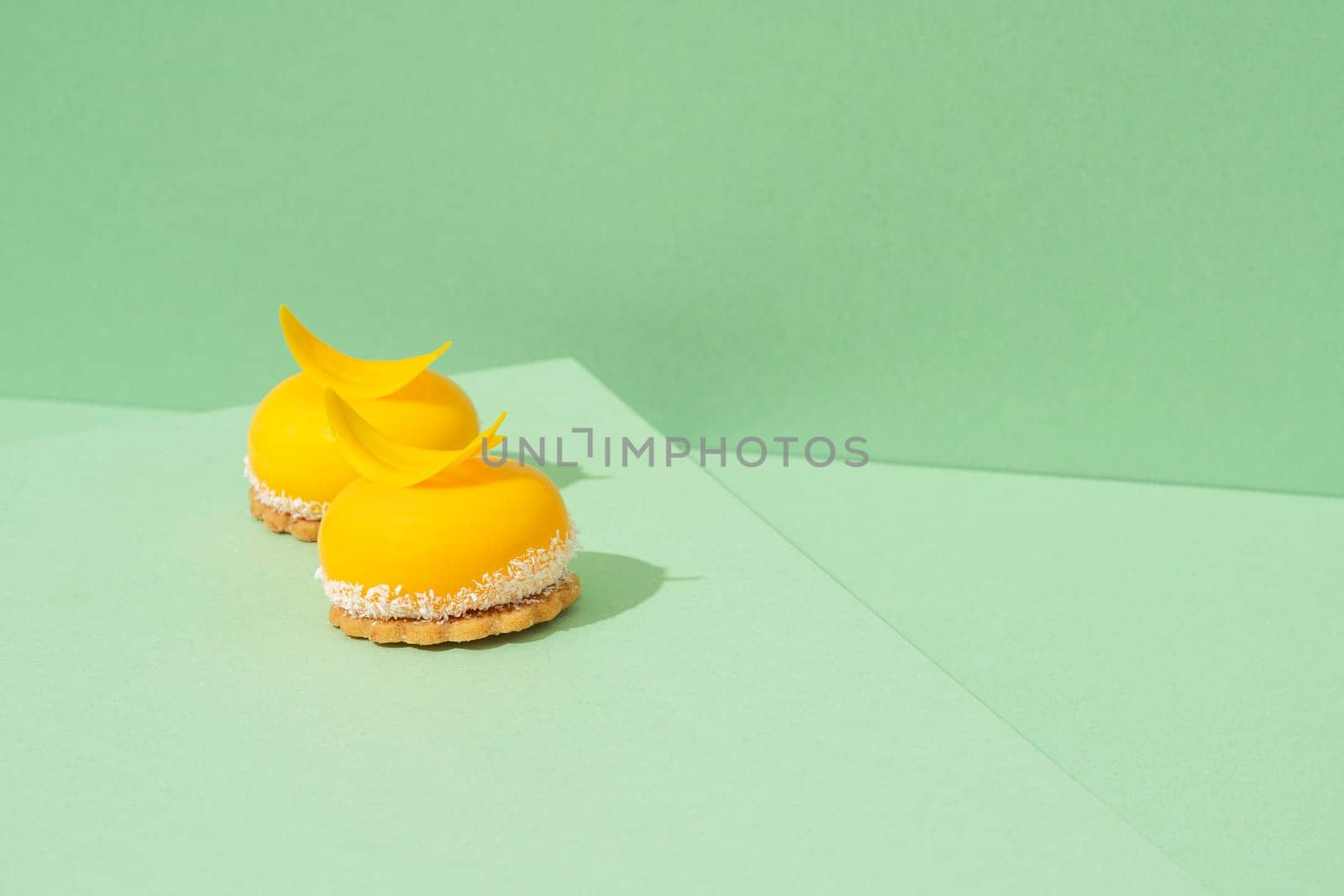 A tray of freshly baked yellow cupcakes with delicious white whipped icing on top and green background by A_Karim