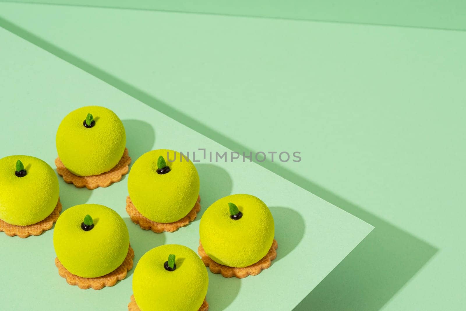 A platter of assorted green donut treats sits atop a wooden table