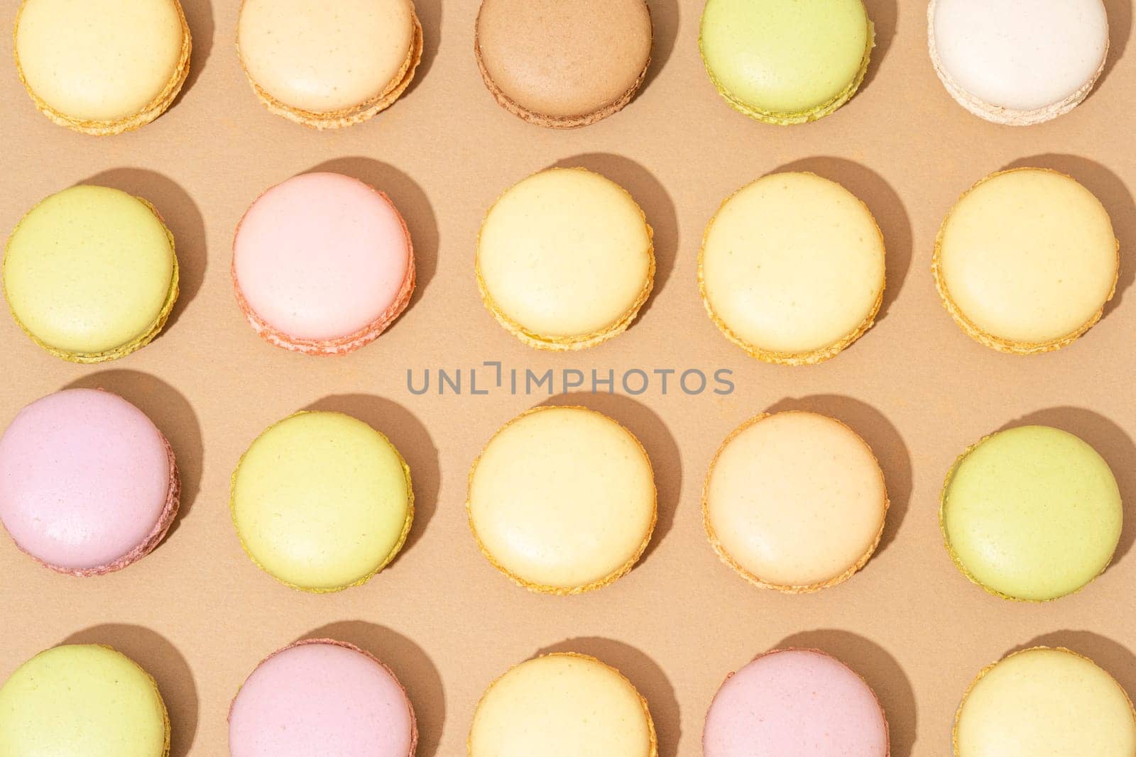 An assortment of macarons are neatly arranged in rows on a flat surface