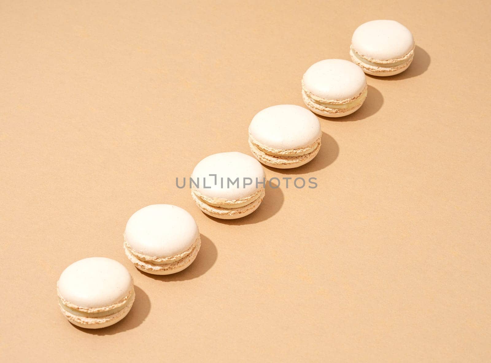 An image of white macaroons on a tan background with plenty of copy space for text or logo overlay