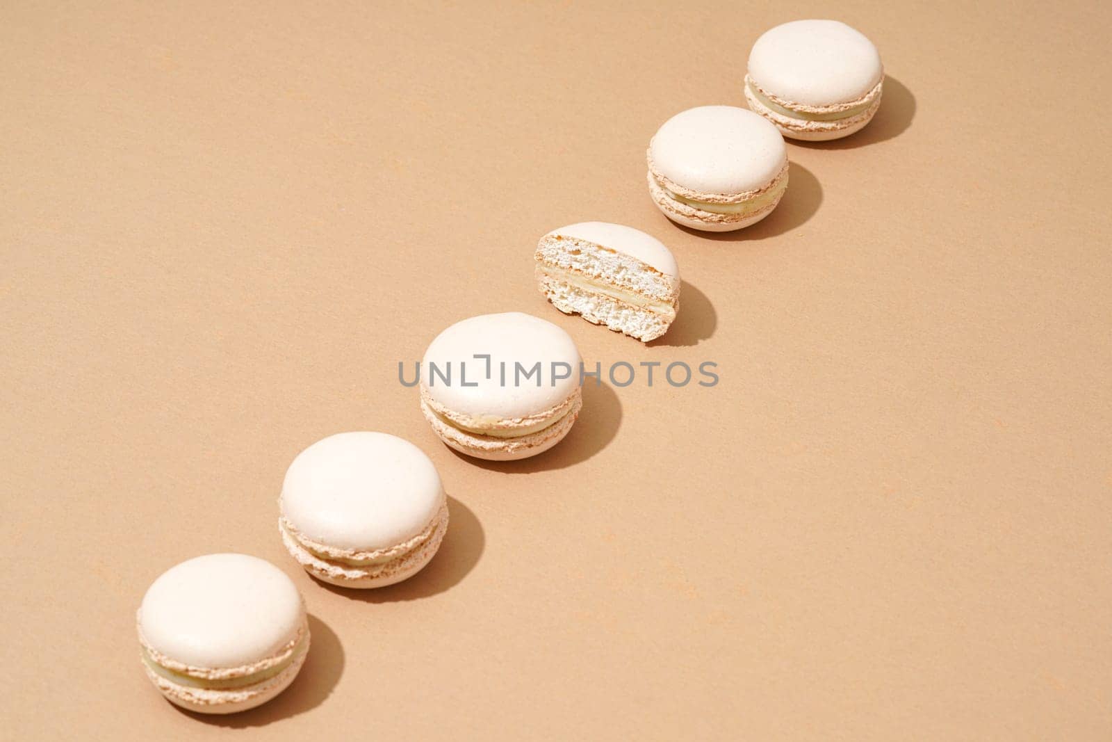 A still life image featuring six white macarons, arranged in a stack on top of each other