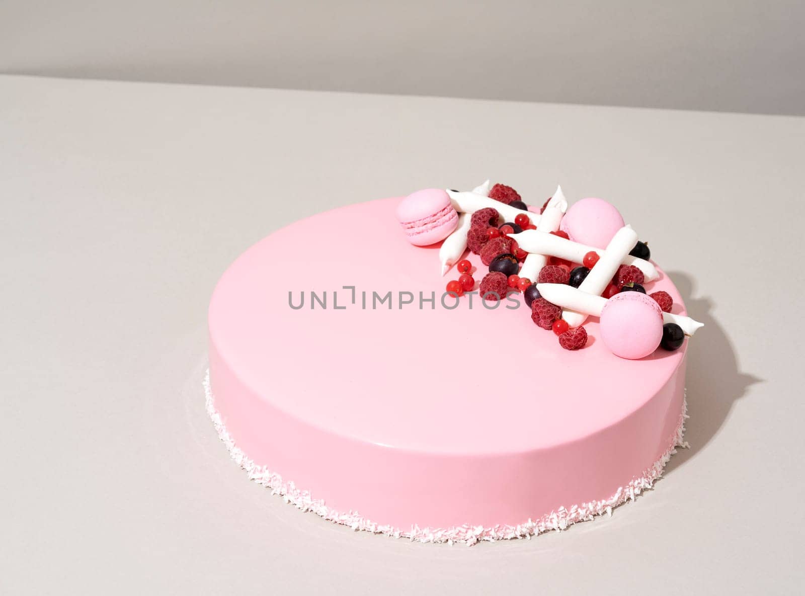 An appetizing pink cake with white strawberries adorning the top sits invitingly on a table by A_Karim