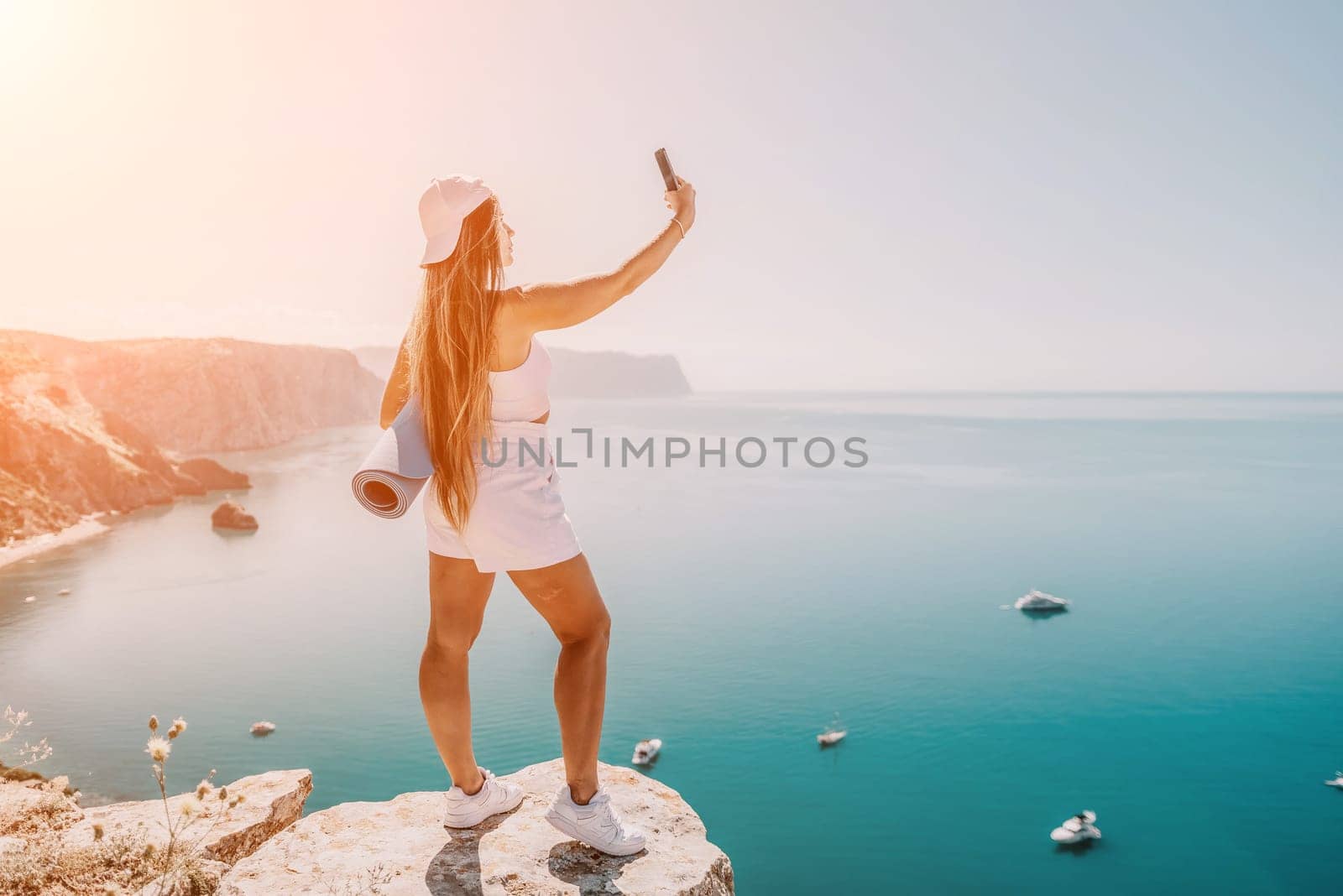 Young woman with black hair, fitness instructor in pink sports leggings and tops, doing pilates on yoga mat with magic pilates ring by the sea on the beach. Female fitness daily yoga concept