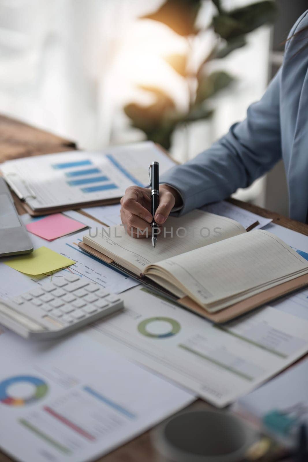 businesswoman hand writing on notebook with pen while sitting at the table in modern office..