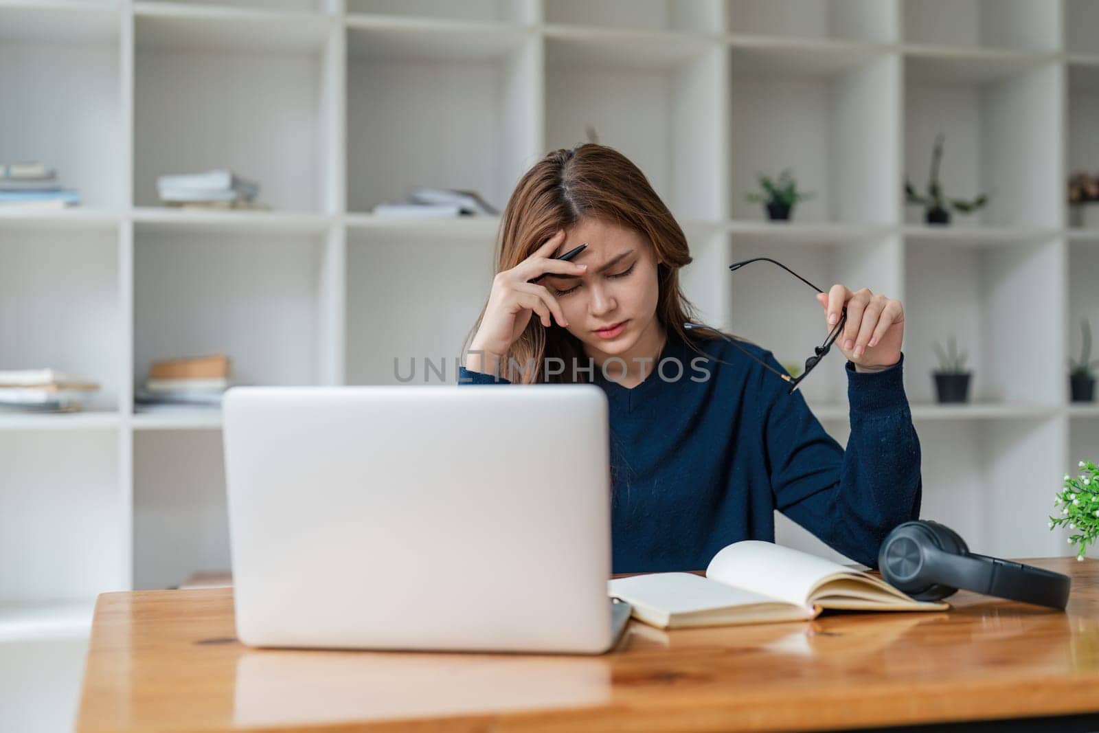 Tired asian woman bored with of laptop sad and frustrated about distance learning or online education sits at desk at home.