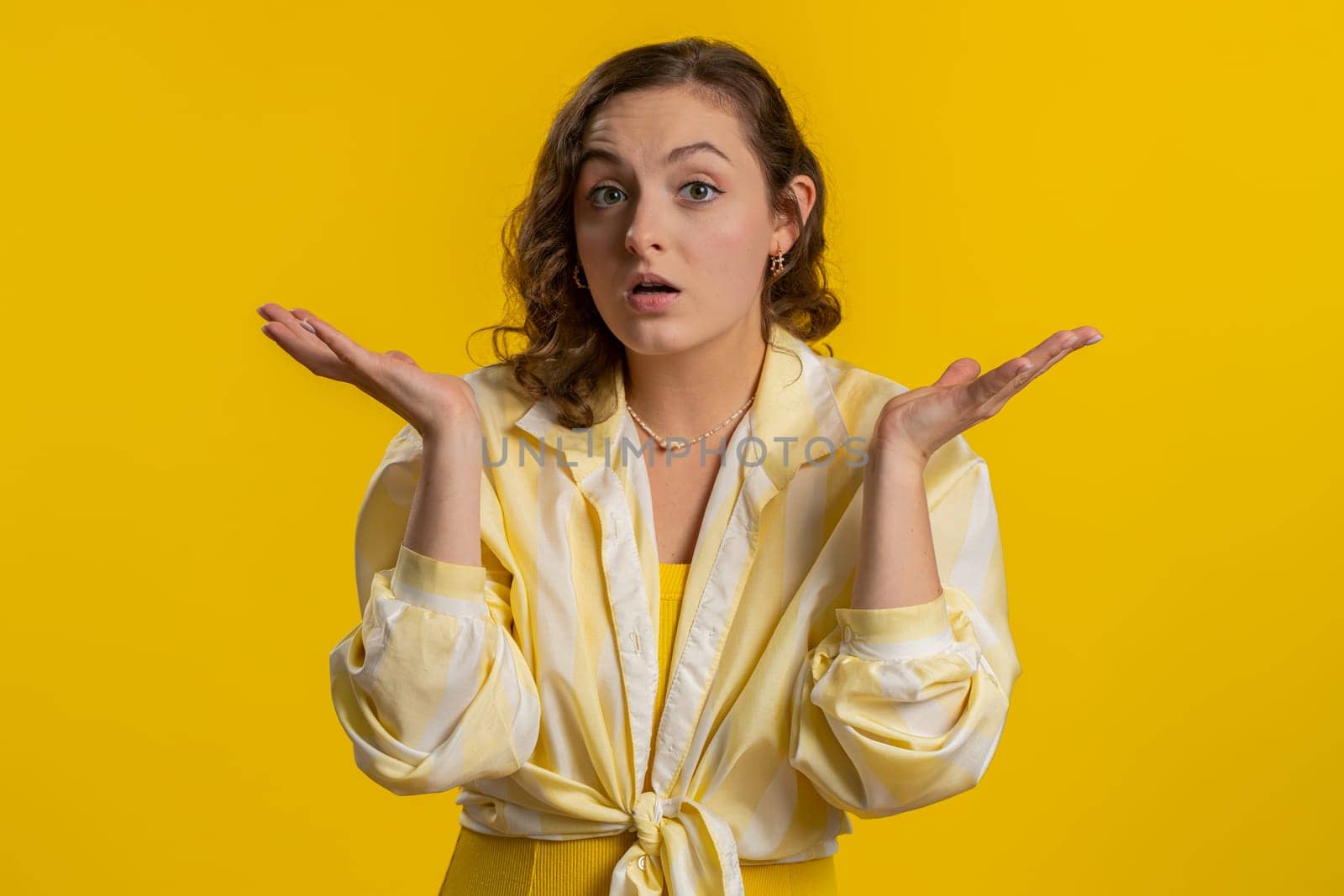 What Why. Sincere irritated young woman raising hands in indignant expression, ask reason of failure demonstrating disbelief irritation by trouble. Pretty confused brunette girl on yellow background