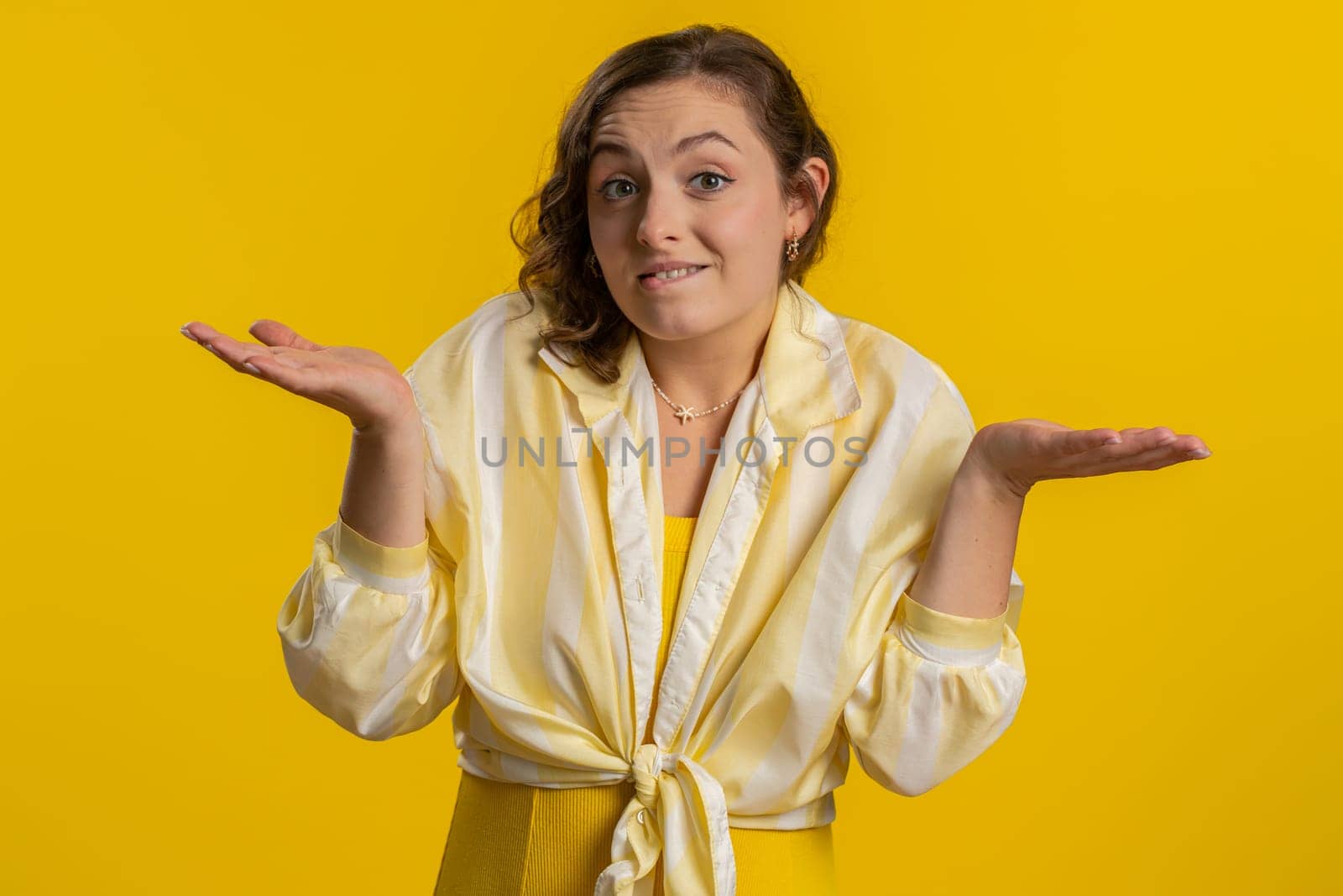 No idea, I dont know answer. Puzzled clueless uncertain attractive woman raising hands in helpless gesture, embarrassed confused by difficult question. Confused one girl on yellow studio background