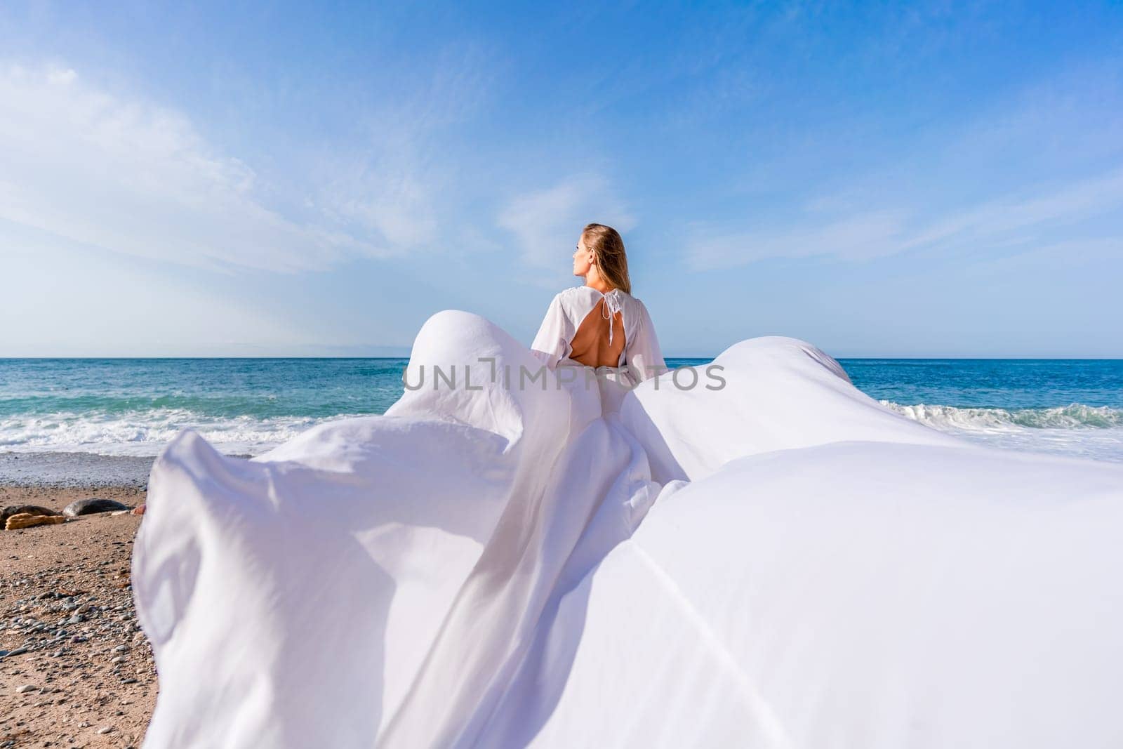 Woman beach white dress flying on Wind. Summer Vacation. A happy woman takes vacation photos to send to friends. by Matiunina