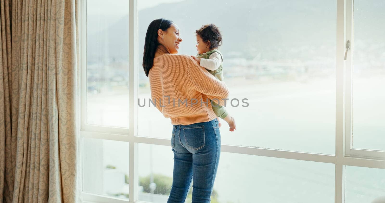 Care, happy and a mother with a baby in a house and looking at the view from a window. Smile, hug and a young mom holding a child for playing, bonding or love together in the morning as family.