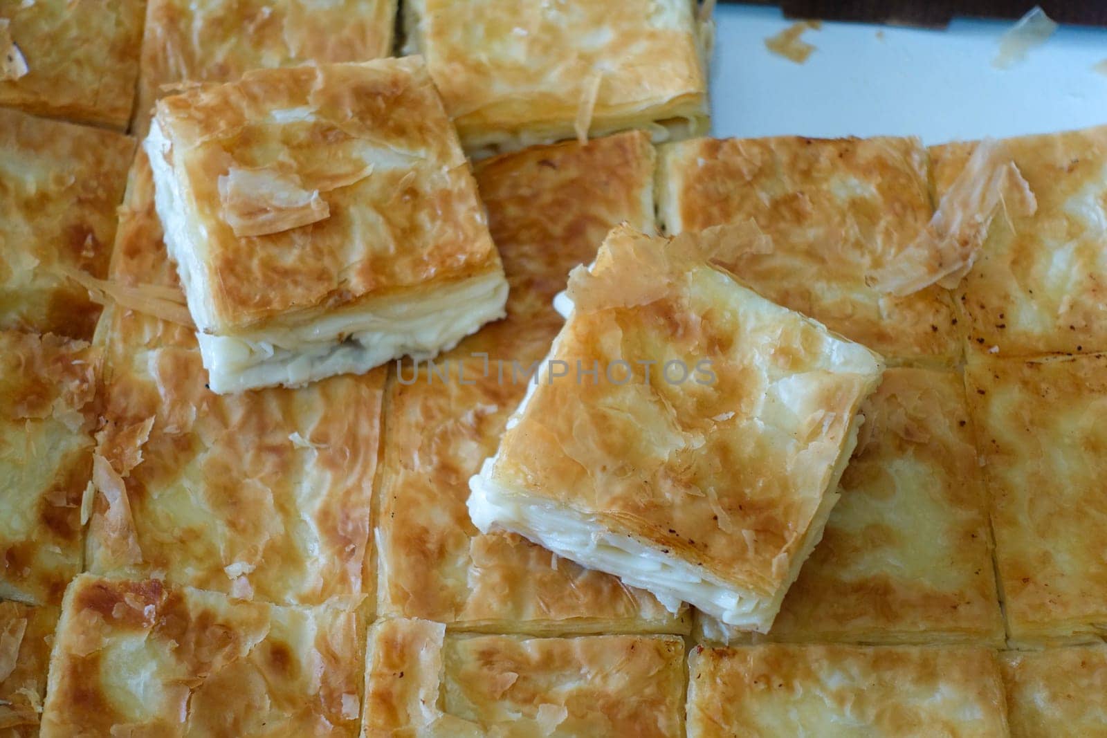 a tray full of pastries,turkish style cheese pie, water borek turkish style close-up, cheese pie,