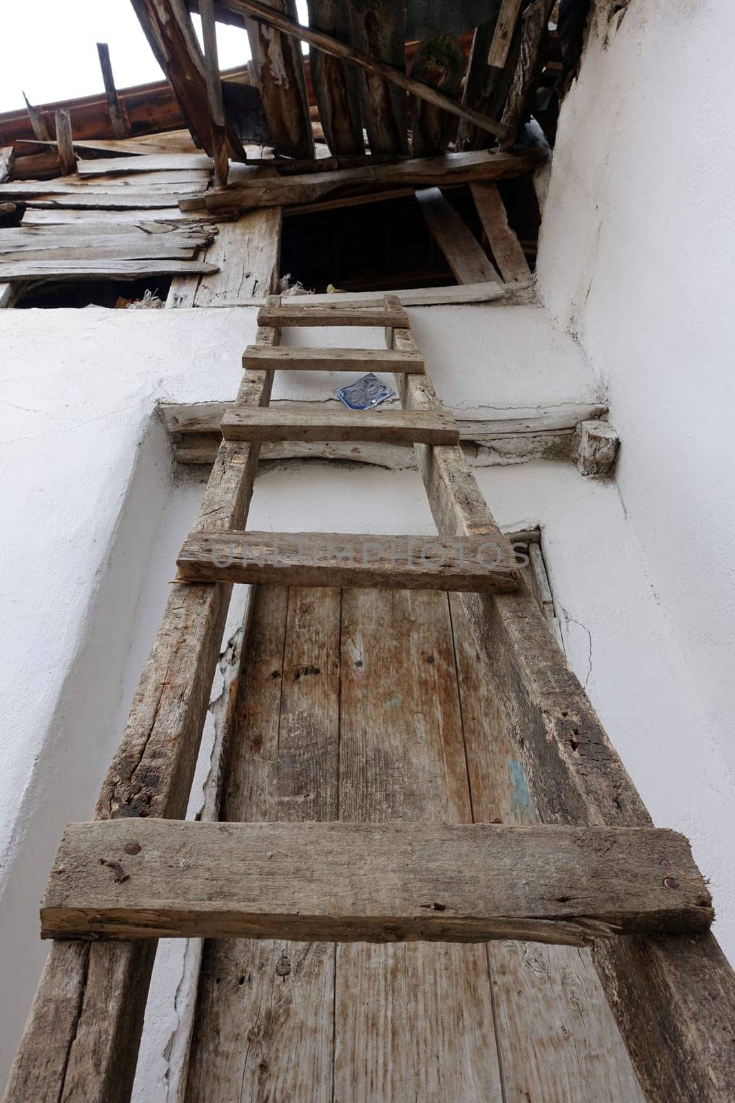 classic handmade wooden ladder for climbing on the roof,The old village house and the wooden ladder placed on its roof, by nhatipoglu