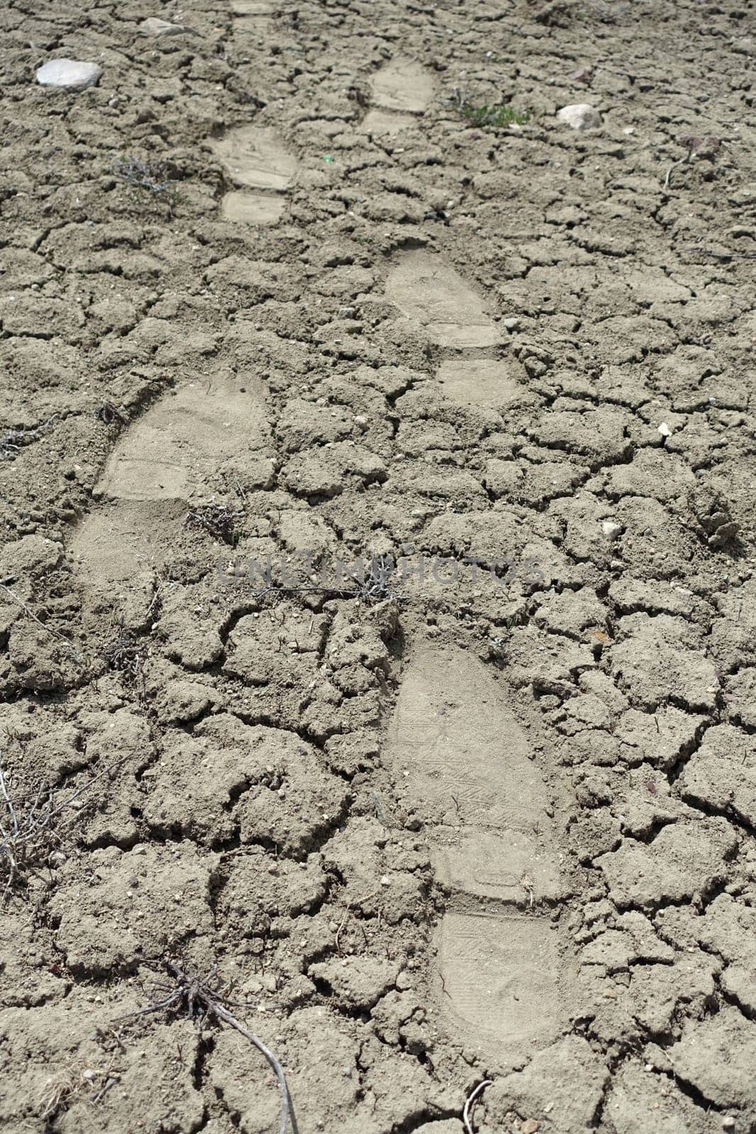 human footprints walking on cracked and cleft soils, human shoe prints in the soil, by nhatipoglu