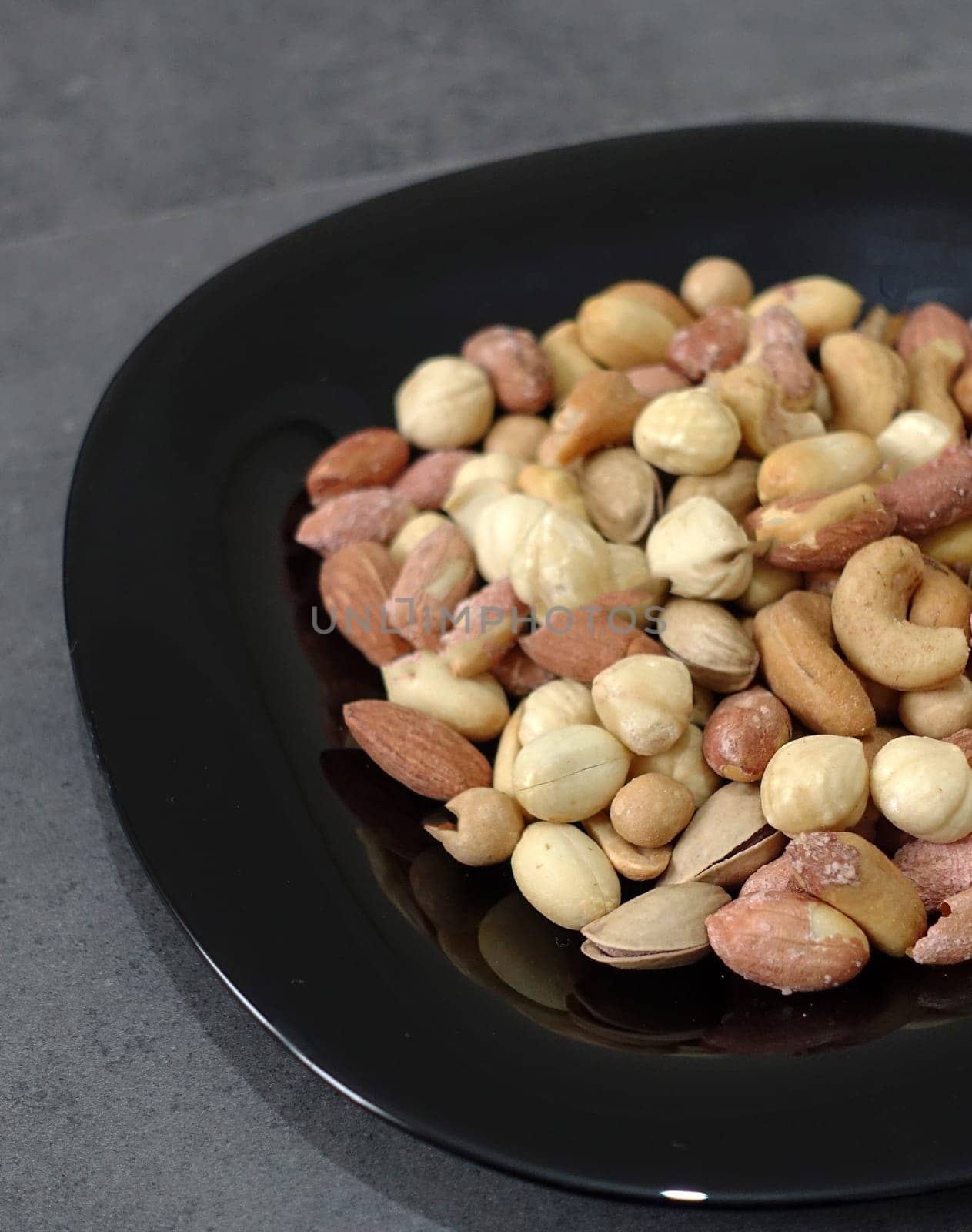 There is a plateful of nuts, hazelnuts, peanuts, cashews in the plate.