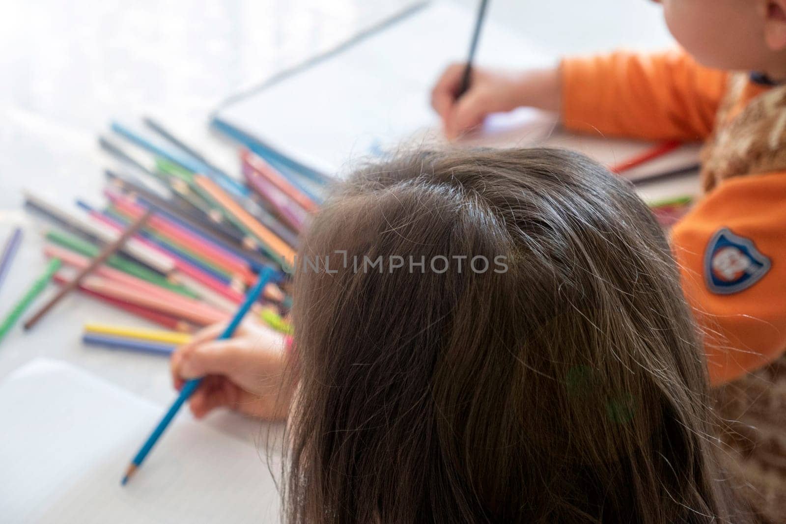 little girl coloring with crayons at the table,close-up of kindergarten kids coloring,