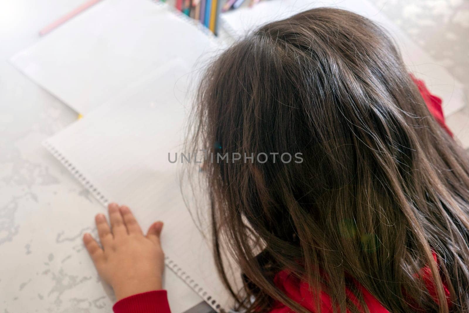 little girl coloring with crayons at the table,close-up of kindergarten kids coloring,