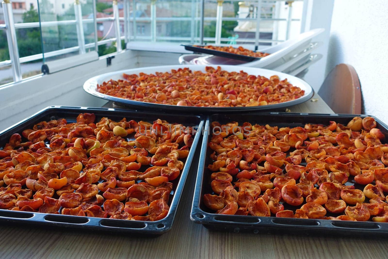 drying apricots in a metal tray on the balcony of the house, drying apricots in the sun, natural fruit drying process,