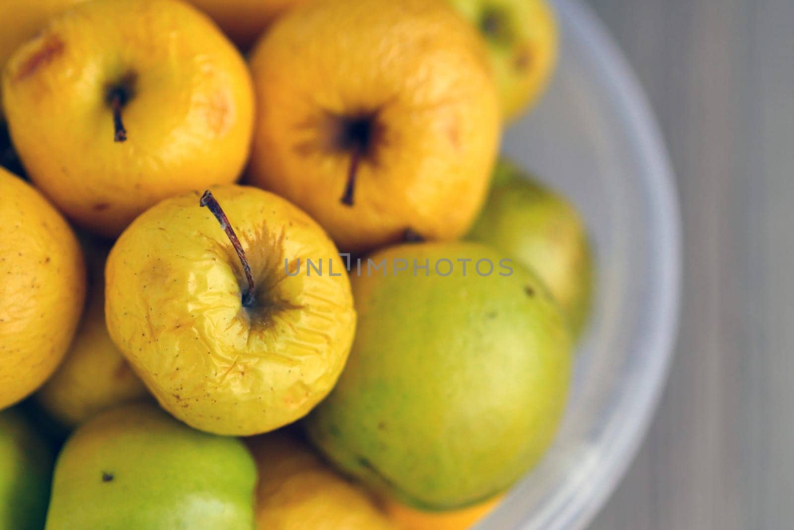 Rotting yellow apples, shriveled apples that have been sitting in a bowl for a long time, by nhatipoglu