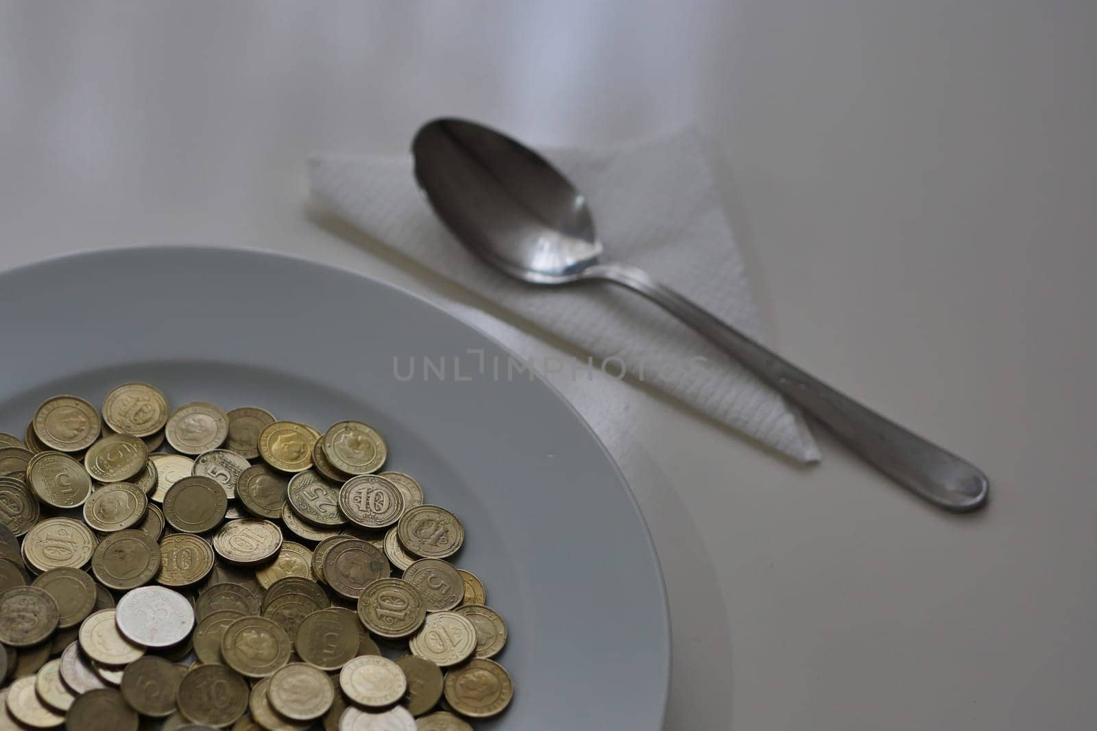 a plate full of coins on a table and a spoon next to it, spending money,