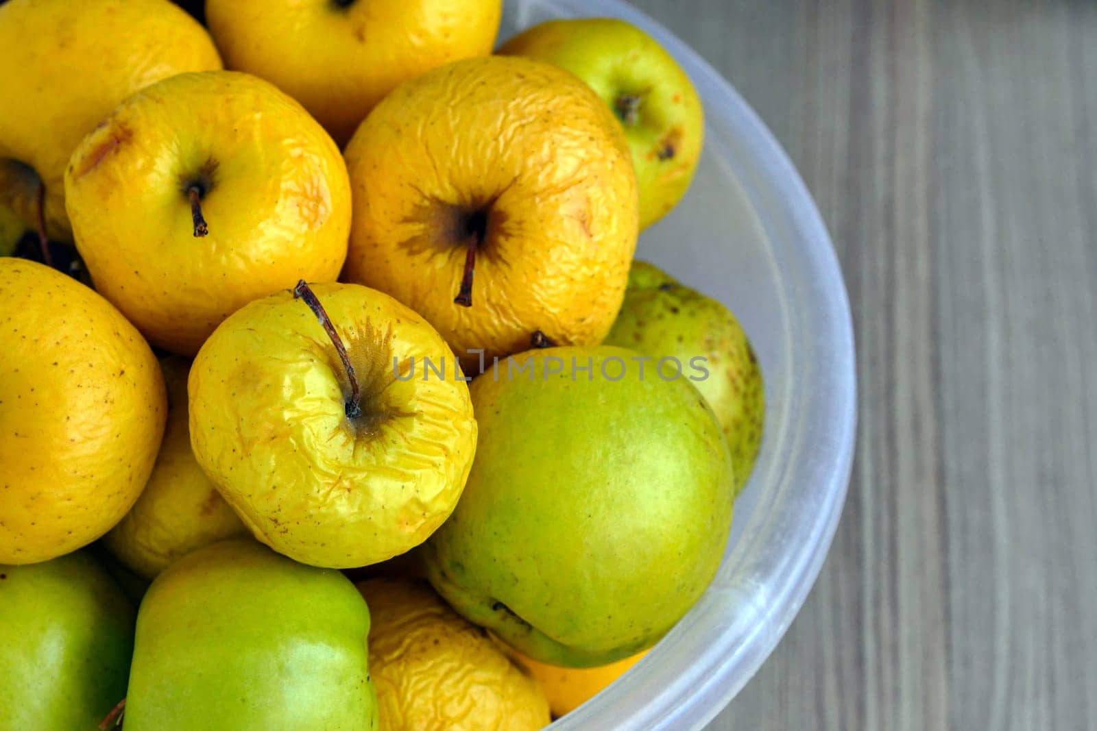 Rotting yellow apples, shriveled apples that have been sitting in a bowl for a long time,