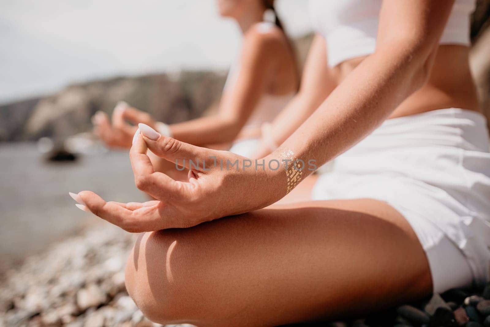 Woman sea yoga. Happy women meditating in yoga pose on the beach, ocean and rock mountains. Motivation and inspirational fit and exercising. Healthy lifestyle outdoors in nature, fitness concept. by panophotograph
