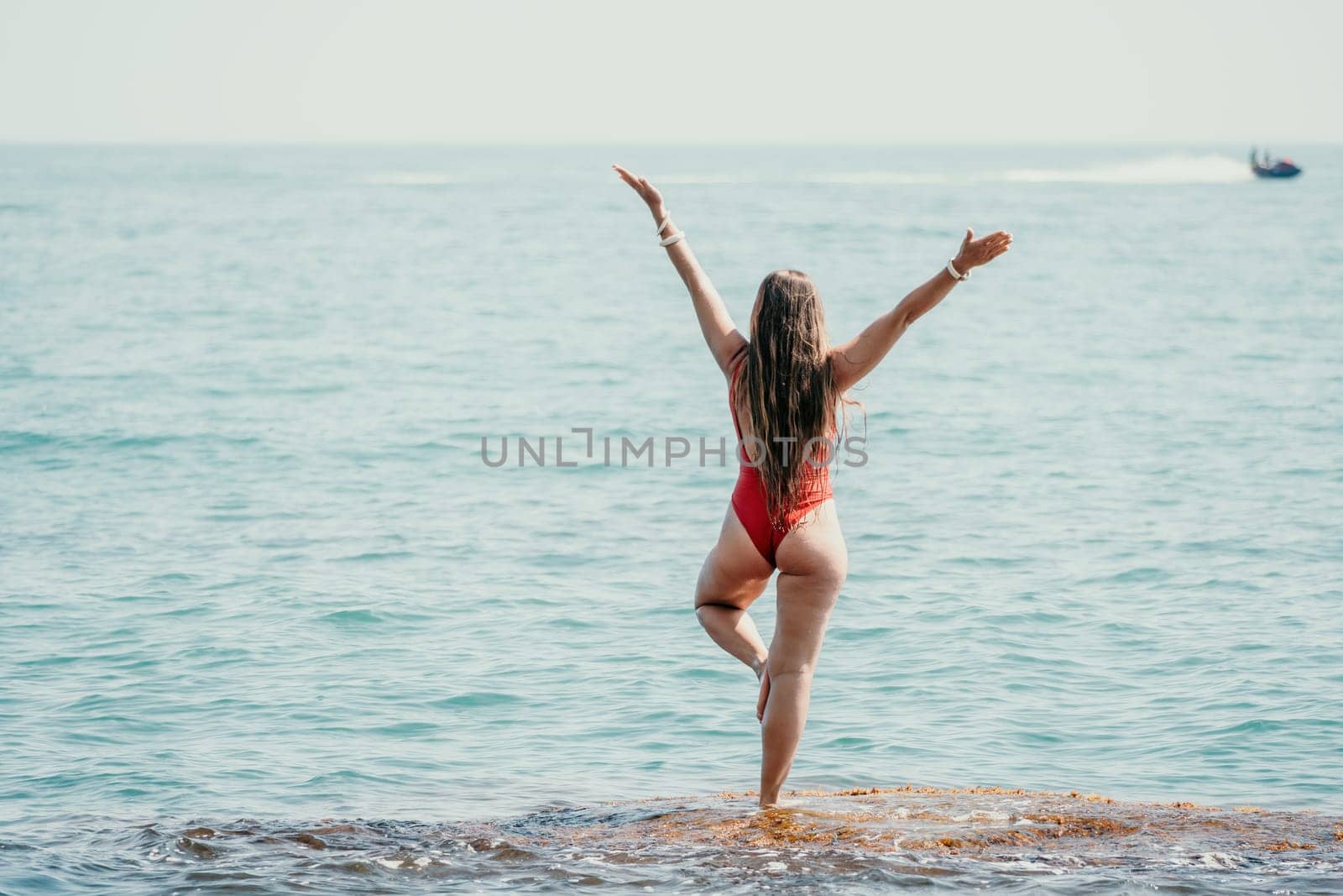 Woman sea yoga. Back view of free calm happy satisfied woman with long hair standing on top rock with yoga position against of sky by the sea. Healthy lifestyle outdoors in nature, fitness concept.