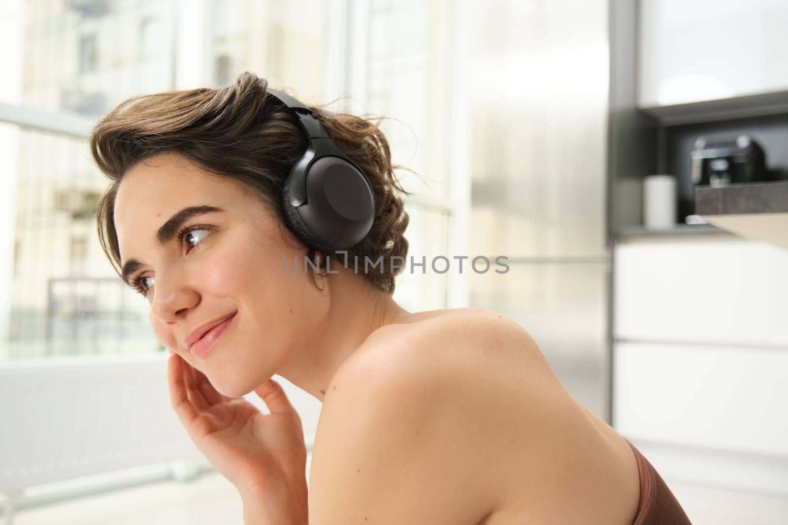Close up portrait of brunette fitness girl, workout from home, looking at video exercises, online gym instructor, listens music in headphones while training pilates, yoga session.