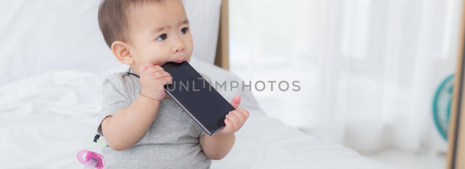 Portrait of cute little baby girl sitting with cozy on bed at bedroom, happiness of toddler, newborn 6-11 months with innocence and expression with cheerful, child charm, indoors, one person.