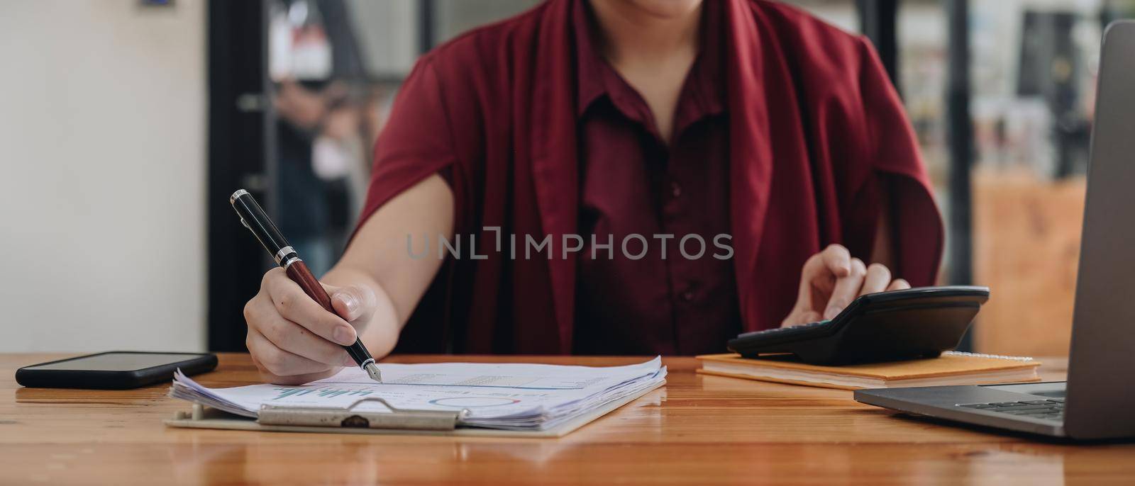 Business woman entrepreneur using a calculator to calculating financial expense at office. financial accounting concept by nateemee