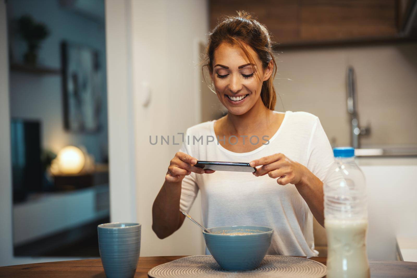 Beautiful young woman is filming her blog broadcast about healthy food at home.