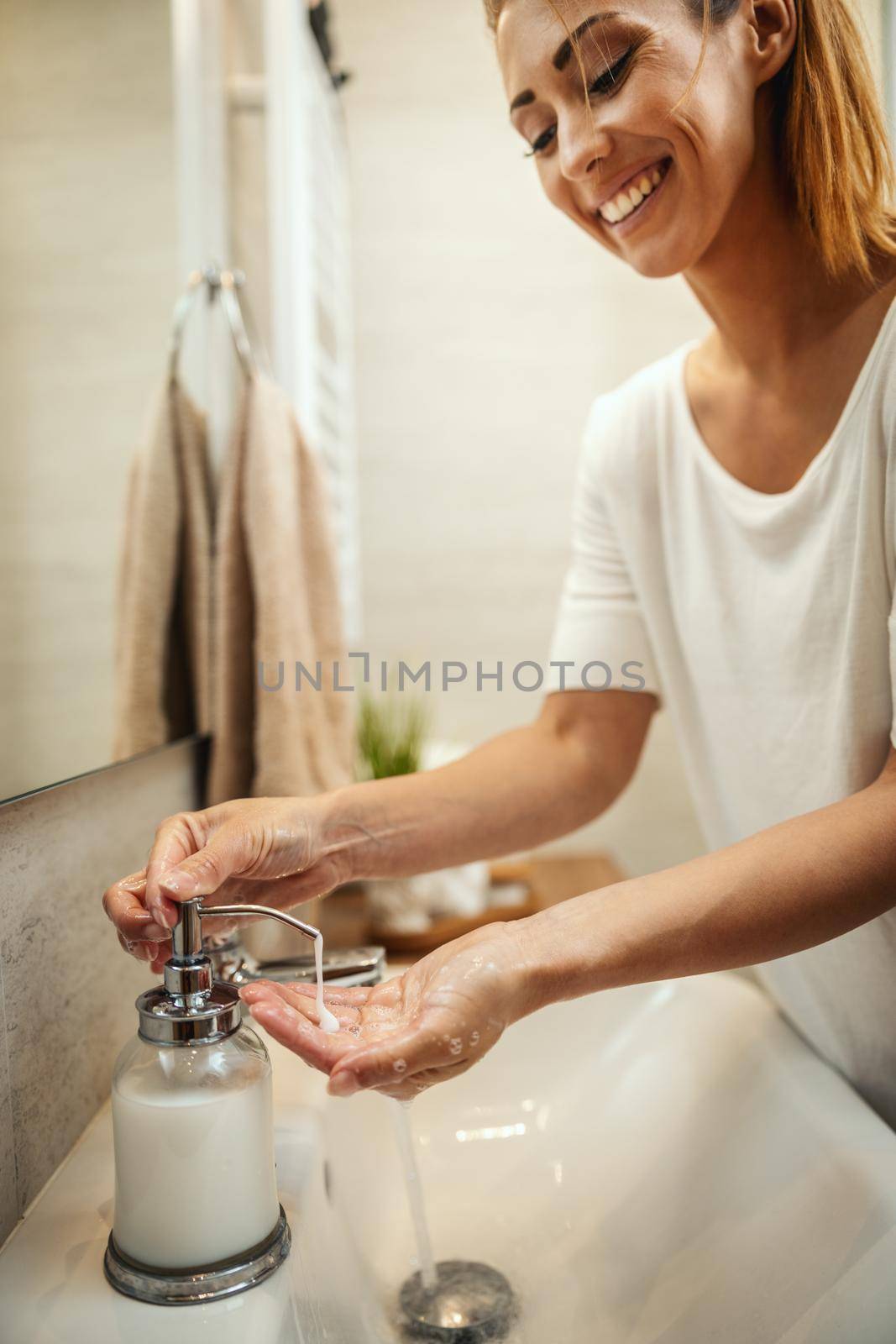 Smiling woman washing her hands with soap to prevent Coronavirus.