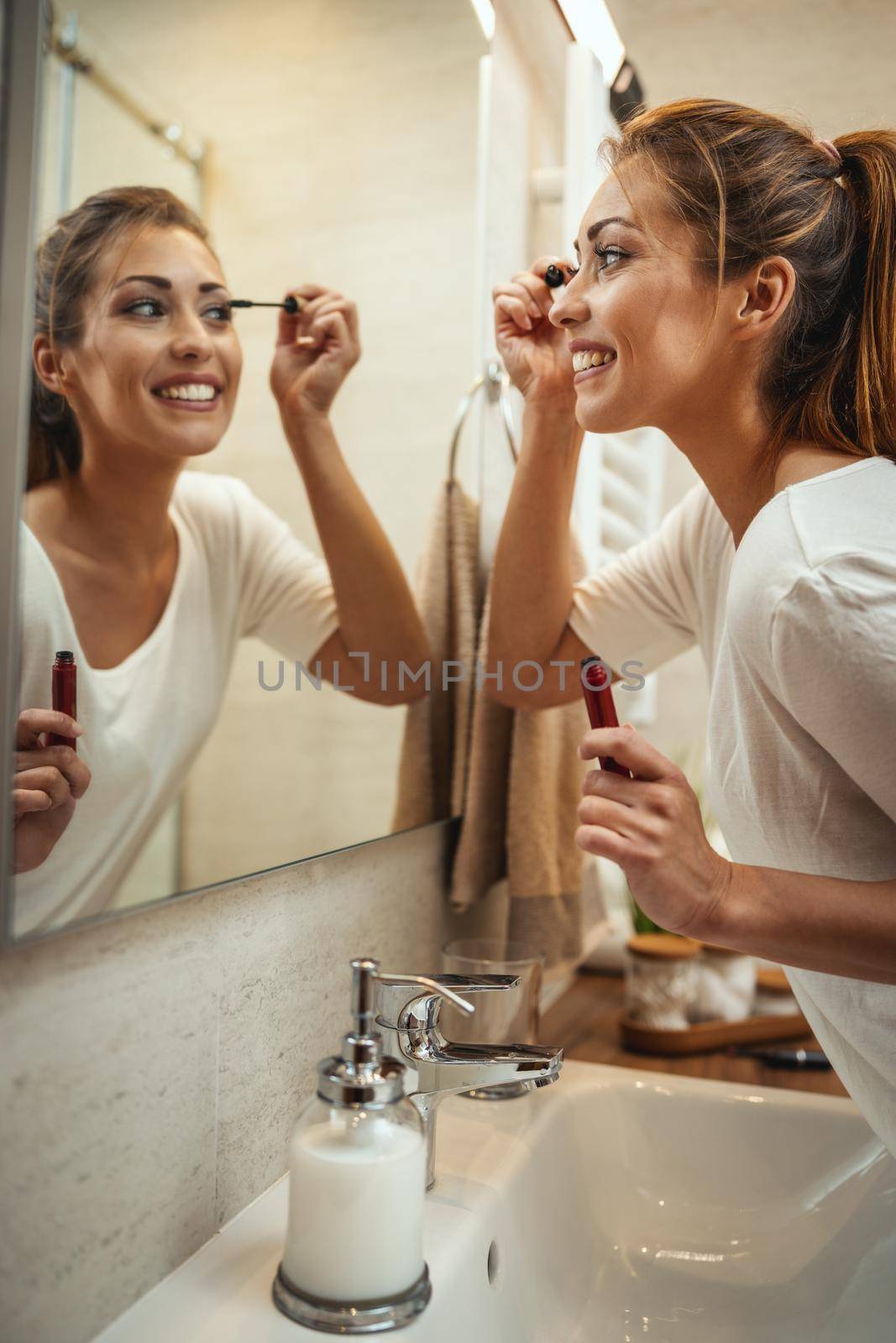 Shot of an attractive young woman applying mascara on mirror in the bathroom at home.