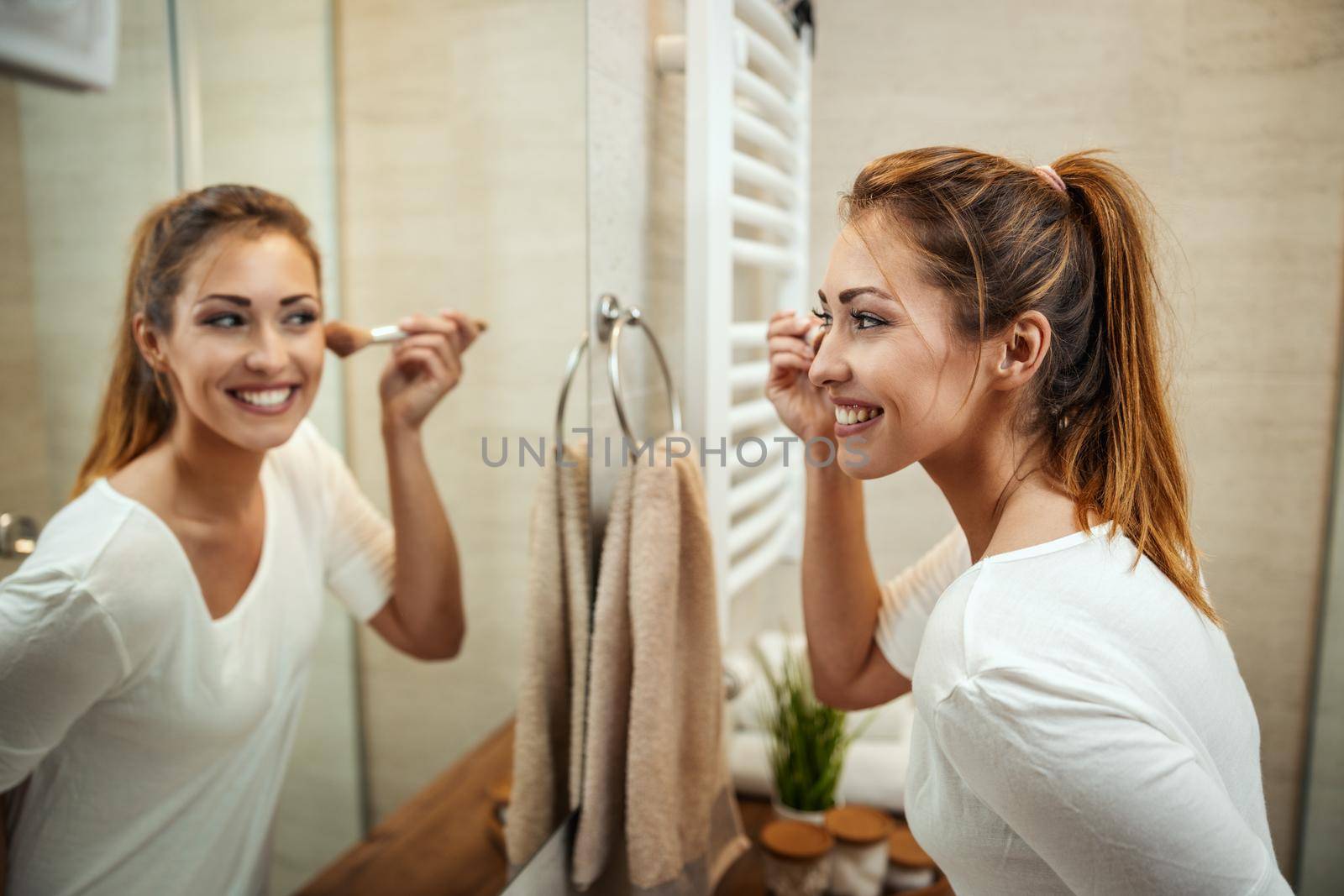 Shot of an attractive young woman applying powder on mirror in the bathroom at home.