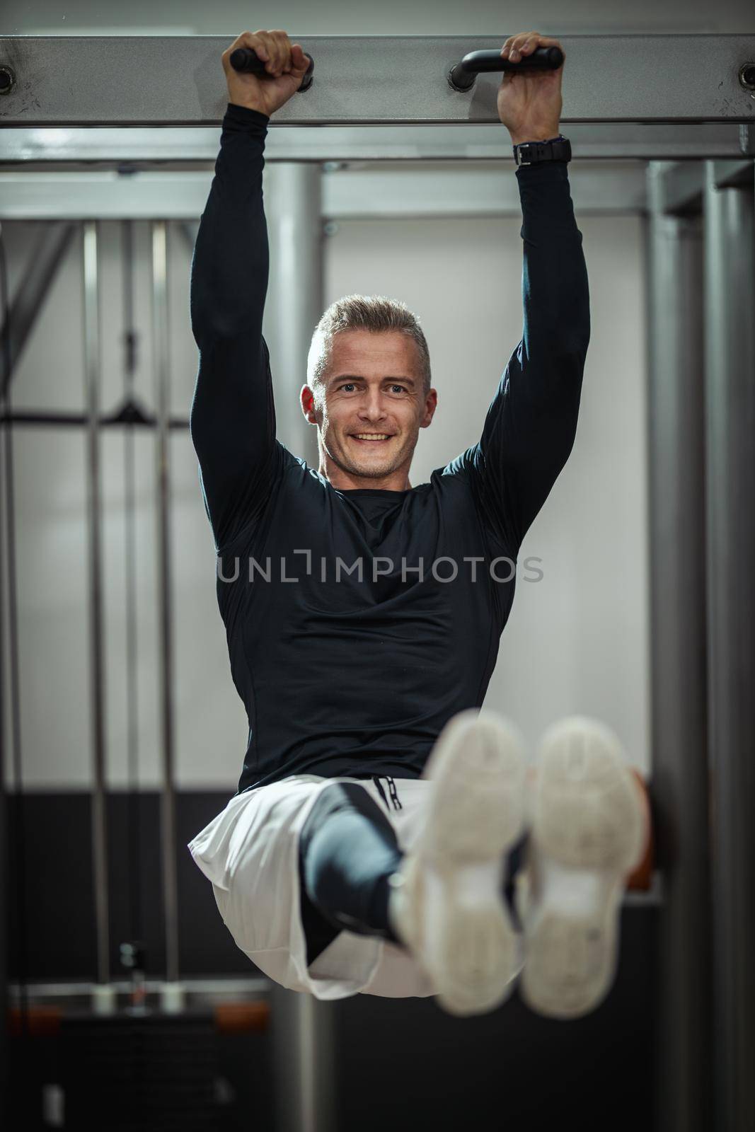 Muscular young man in sportswear focused on doing sit-up exercises during a strength training workout at the gym.
