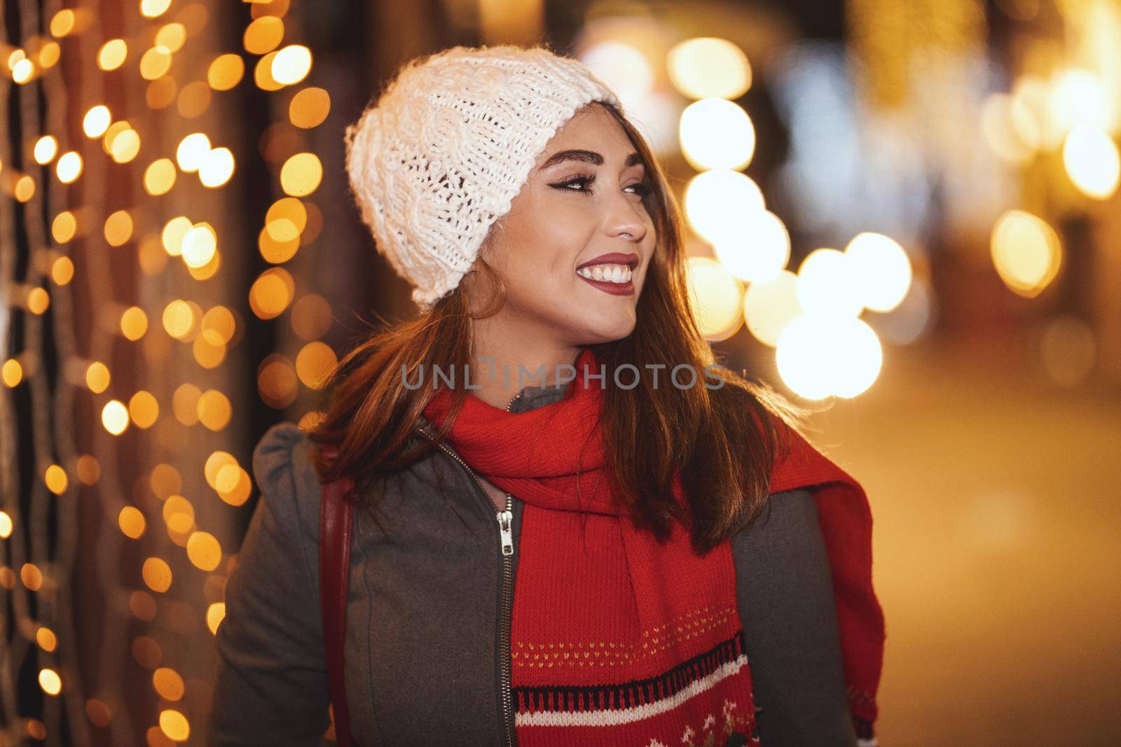 Cheerful young woman is having fun and walking in the city street at Christmas time.