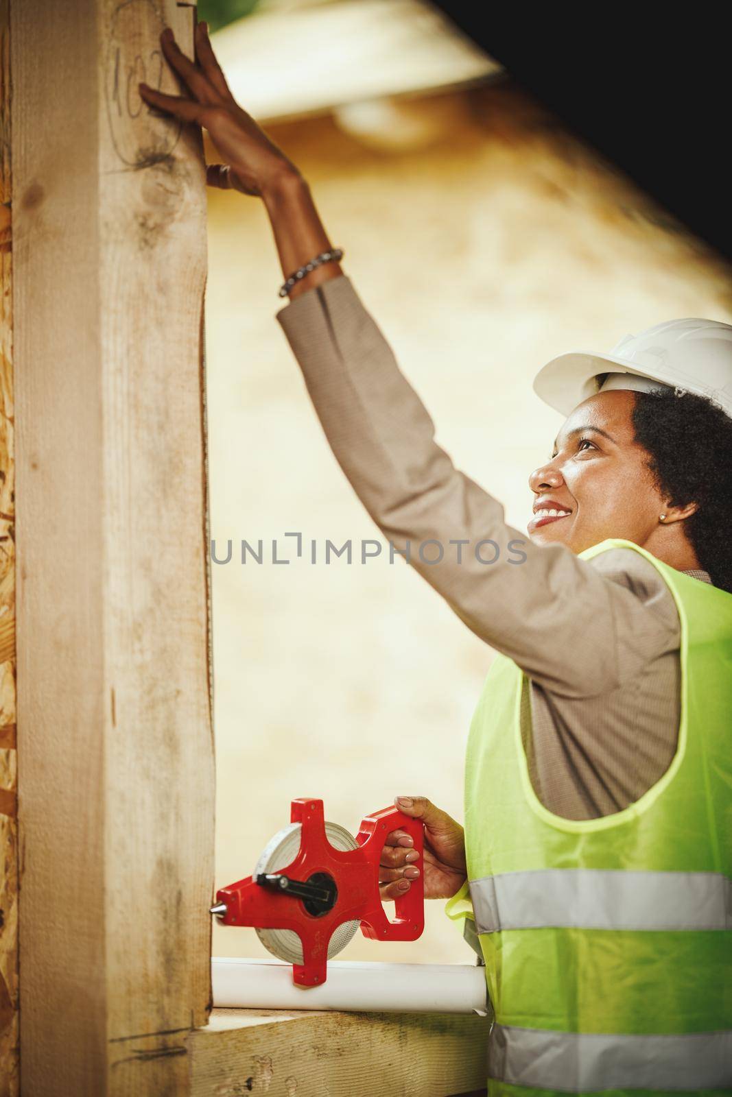 Shot of an African female architect measuring a window of new wood house.