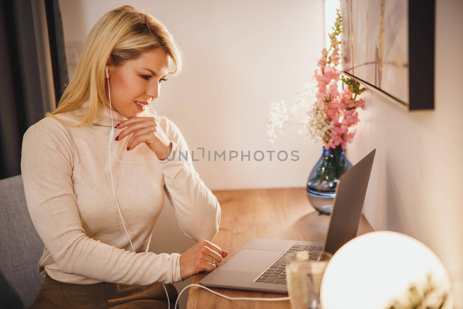 Shot of a young business woman working online from home. She is using her laptop and having video conference at cozy atmosphere during pandemic Covid-19 virus.