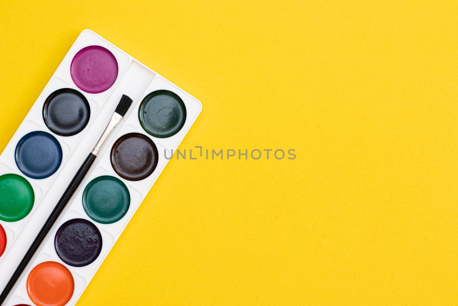 Watercolor paints on a yellow background . Paints for drawing. Hobbies and recreation. Office supplies. School supplies. Copy Space