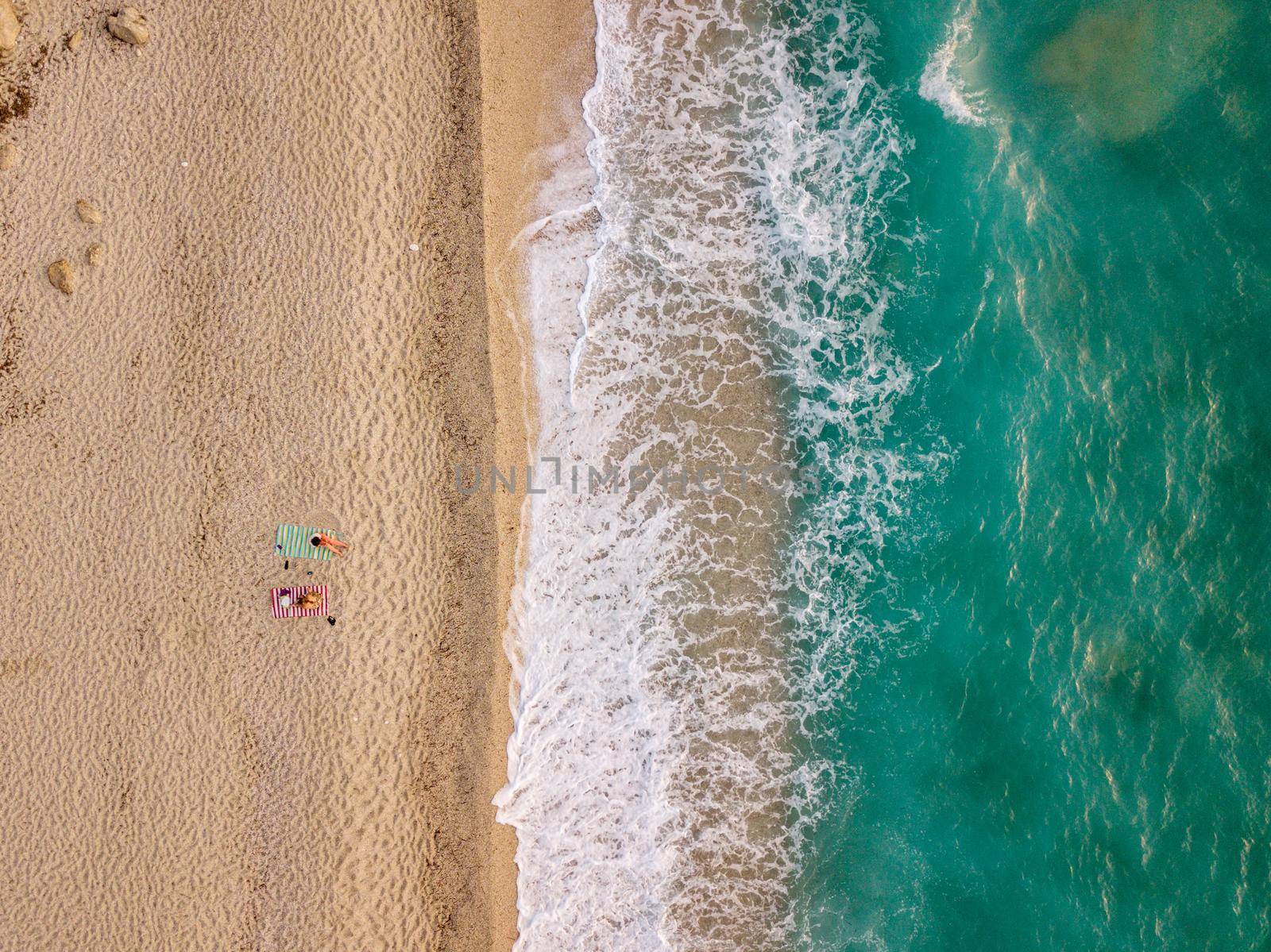 Aerial view of the amazing idyllic beach with two lonely people near waved clear Mediterranean sea at sunny day.